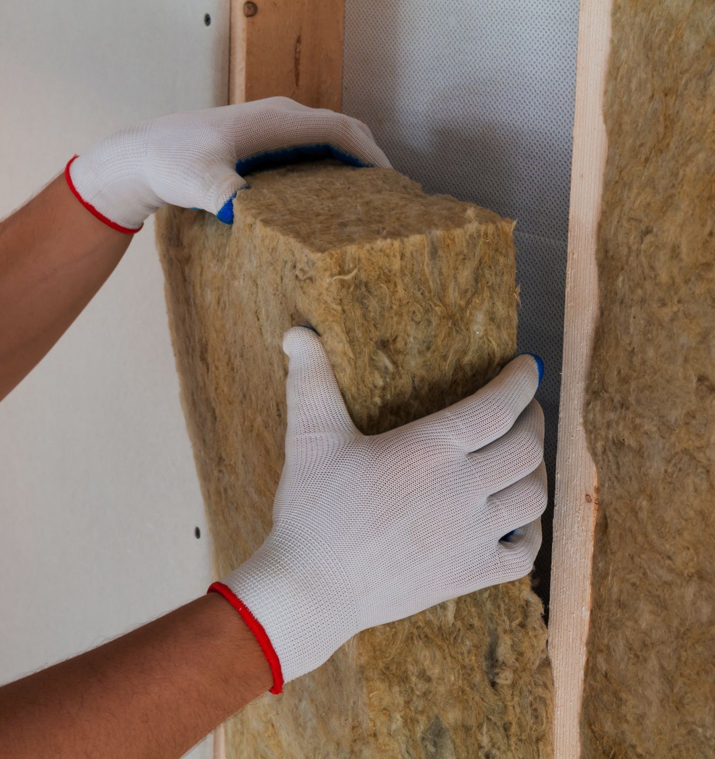 someone adding a block of insulation into a timber frame